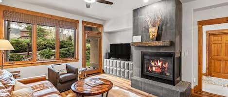 A living room with a fireplace, leather sofa, and a television.
