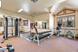 A gym with various exercise equipment, including dumbbells, a bench press, and a squat rack.