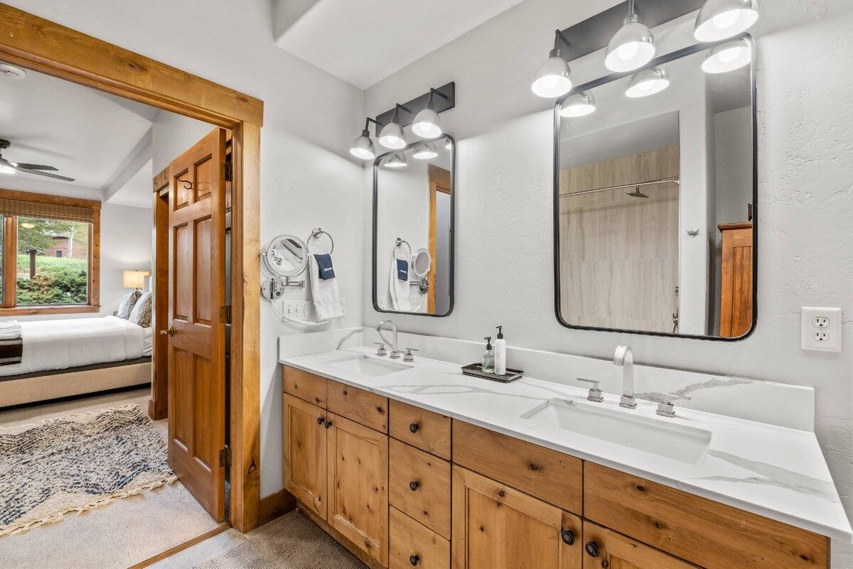 A bathroom with a double sink, wooden cabinets, and a large mirror.