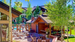 A patio area with outdoor seating, a pool, and a building with a sloped roof.