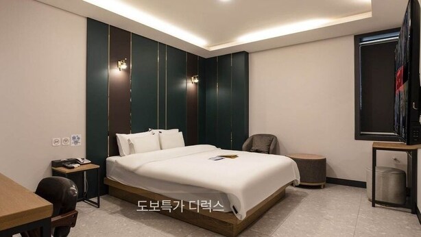 Una habitación de hotel moderna con cama, escritorio, silla y televisor.