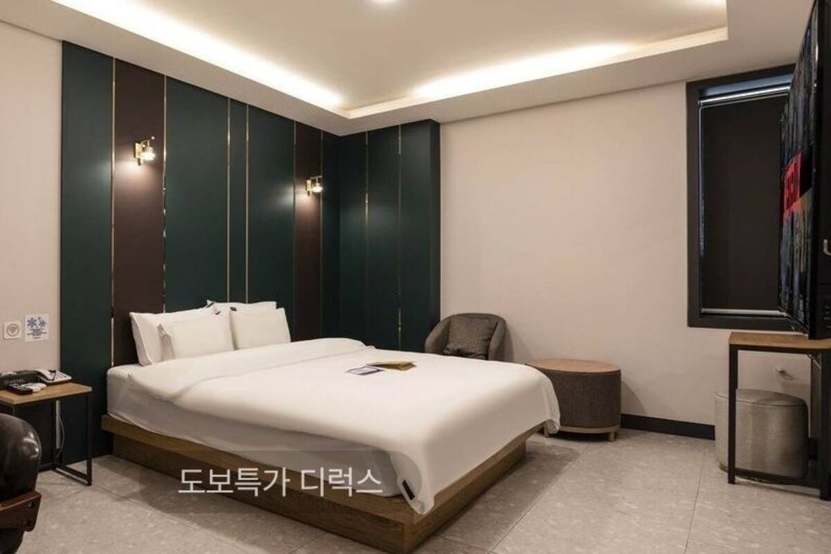A modern hotel room with a bed, desk, chair, and a TV.