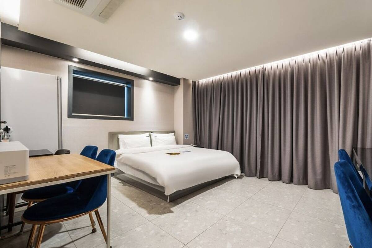 A modern hotel room with a bed, a desk, and a chair.