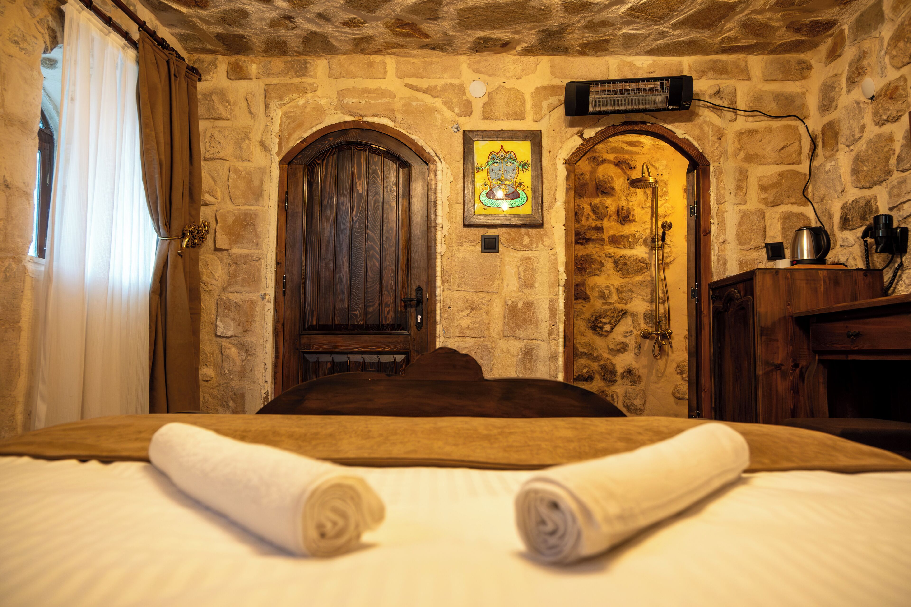 A room with a stone wall, a wooden door, and a framed picture on the wall.