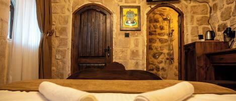 A room with a stone wall, a wooden door, and a framed picture on the wall.