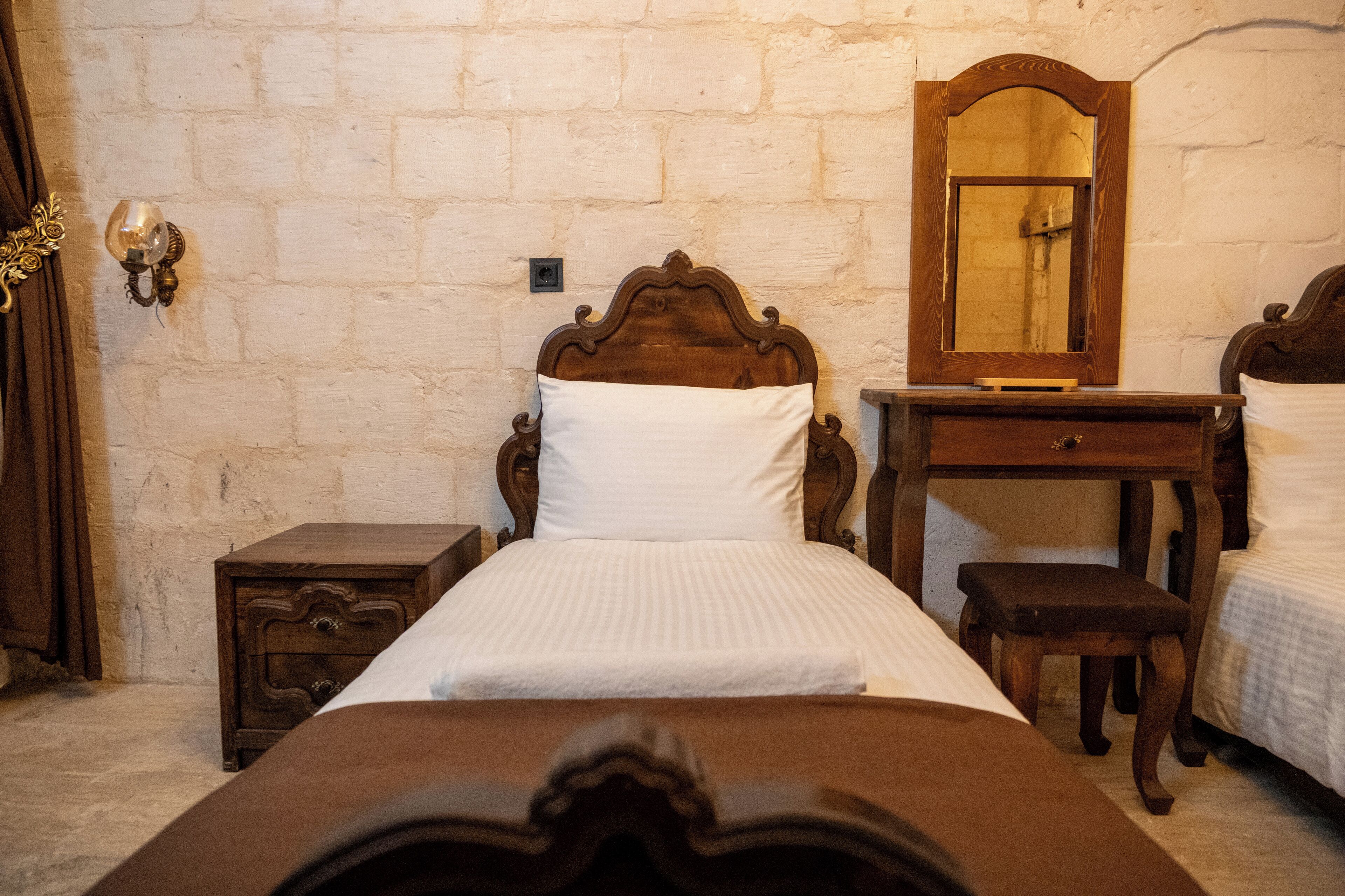 Ein Schlafzimmer mit einem hölzernen Bett, einem Nachttisch, einer Kommode und einem Spiegel.