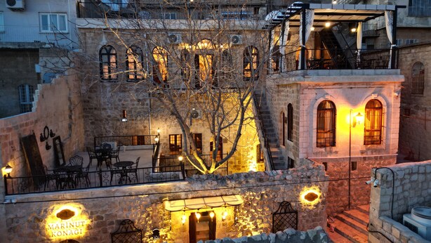 A stone building with multiple balconies, outdoor seating, and a sign for 'Marinot Konagi'. - Marinut Konağı (Mardin)