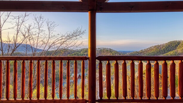 A wooden balcony with a view of a mountainous landscape.