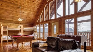 A cozy room with a pool table, a leather sofa, and a foosball table.