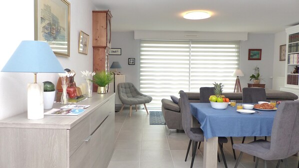 A dining area with a table set for breakfast, featuring a bowl of fruit and croissants.