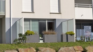 A modern building with large windows, a flat roof, and a small garden area with rocks and plants. - Ty Kerihuel - Luxury flat on the port in Etel (Etel)