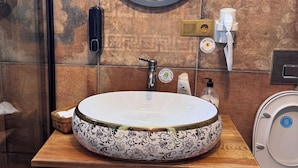 Een badkamer met een rond wastafel, een houten wastafelmeubel en een spiegel.