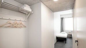 A modern hotel room with a bed, a small bedside table, a chair, and a window with curtains. - Omena Hotel Joensuu (Joensuu)