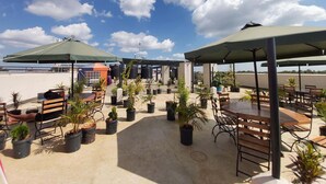 A rooftop patio area with outdoor seating, umbrellas, and potted plants.