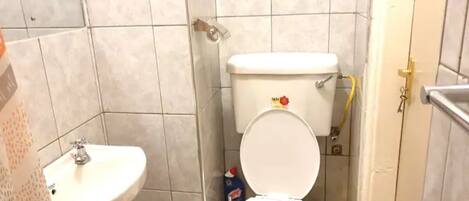 Baño con inodoro, lavabo y paredes con azulejos.