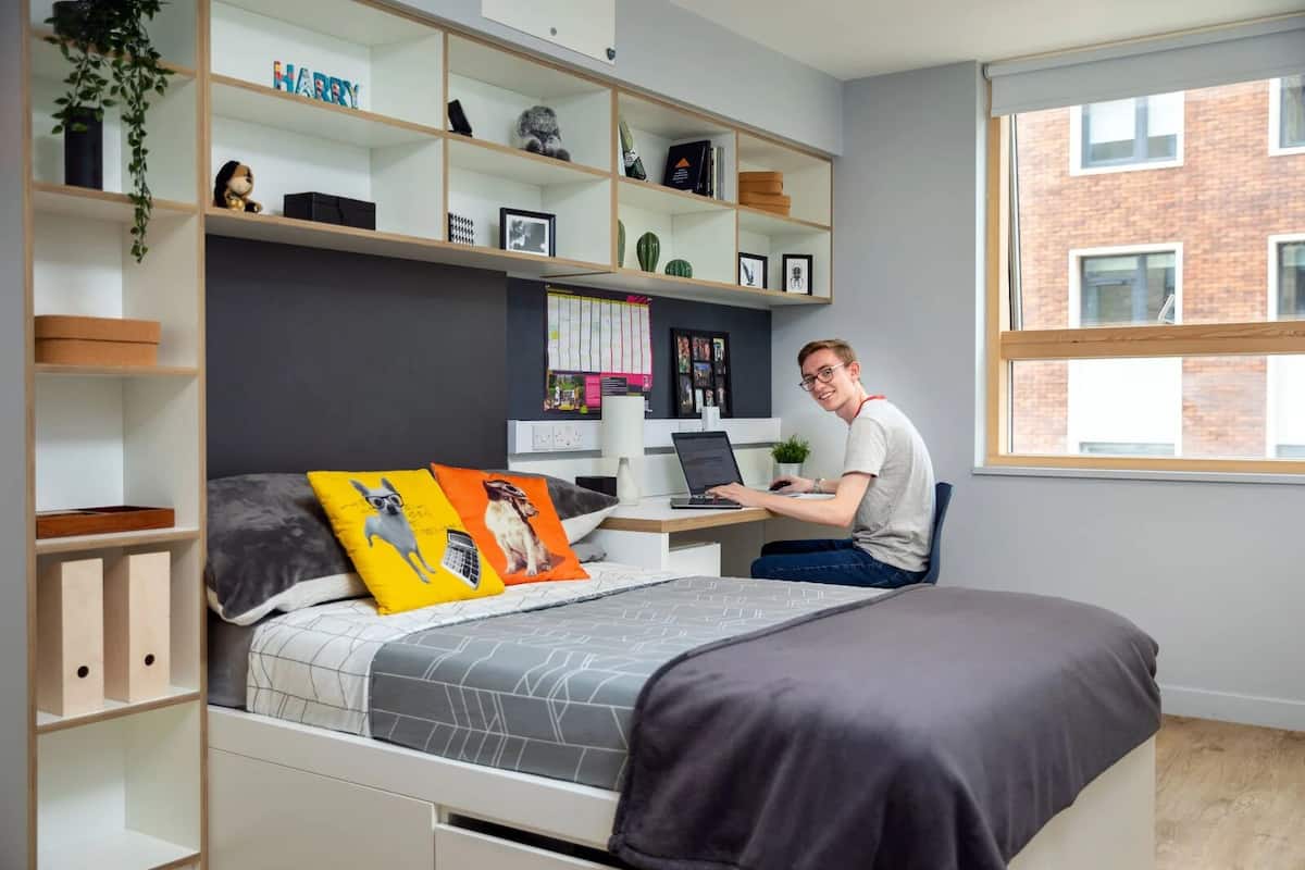 A modern bedroom with a bed, a desk, and a laptop.