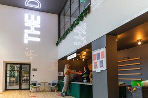 A reception area with a neon sign, reception desk, chairs, and a bulletin board.