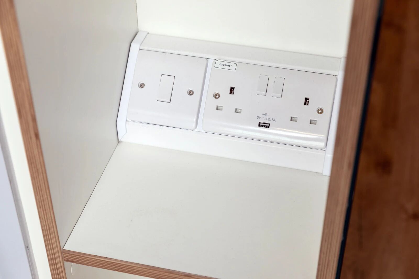Un enchufe blanco con dos interruptores y un puerto USB.