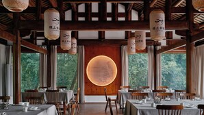 A restaurant with wooden interiors, tables set for dining, and large windows offering a view of greenery. - Jishang Qingcheng Mountain Villa (Chengdu)