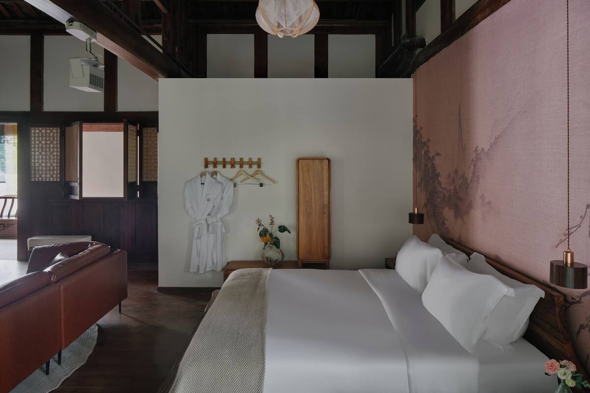 A bedroom with a large bed, wooden headboard, a wardrobe, and a hanging robe rack.