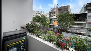 A balcony with a water purifier, potted plants, and a view of neighboring buildings. - Saluton House (Da Nang)