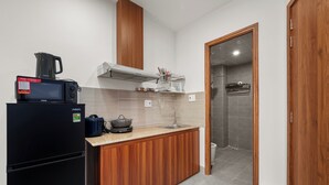 A compact kitchen with a black refrigerator, a microwave, and a coffee maker on the counter. - Saluton House (Da Nang)
