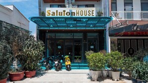 A multi-story building with balconies, a covered entrance, and potted plants. - Saluton House (Da Nang)