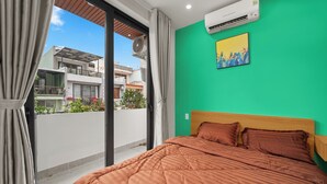 A bedroom with a bed, a green wall, and a window with curtains. - Saluton House (Da Nang)