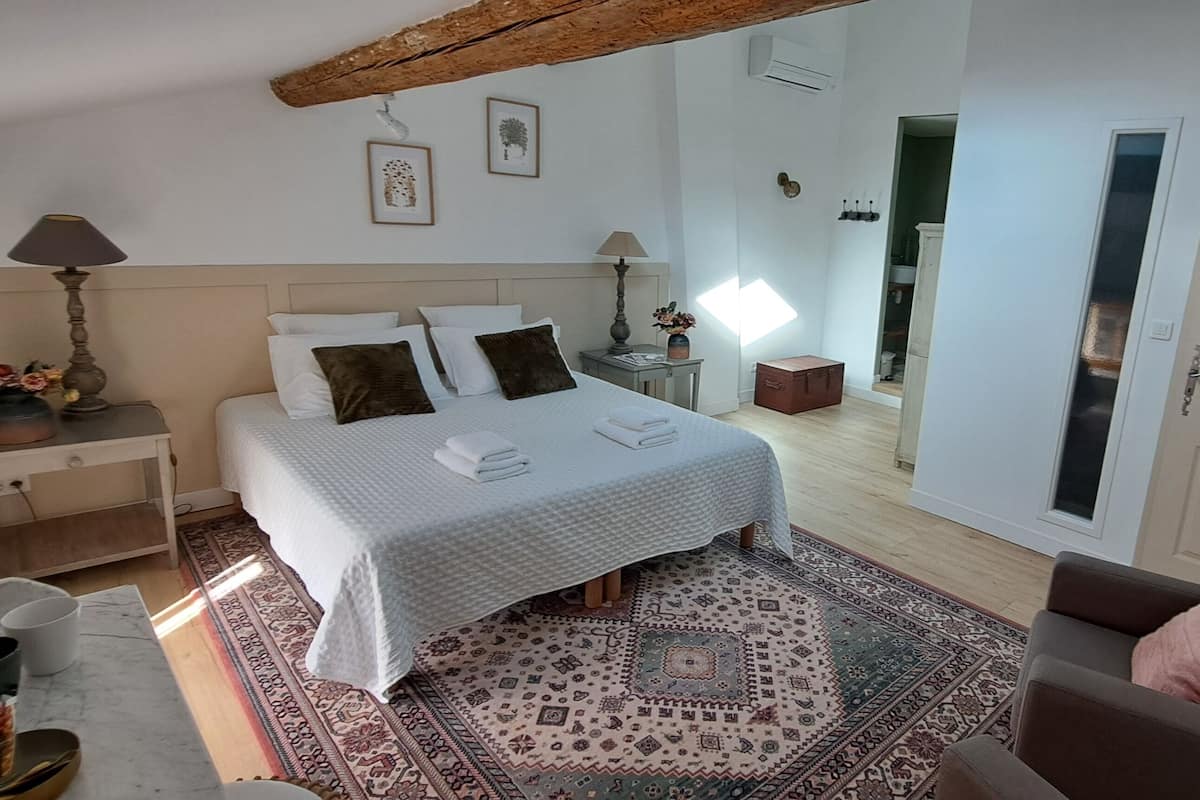 A bedroom with a bed, bedside tables, a chair, a rug, and a door.