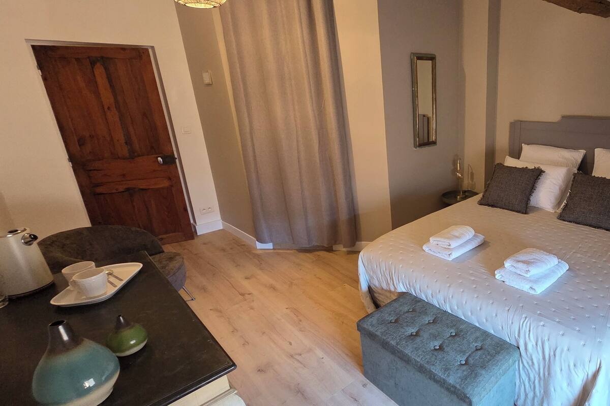 A bedroom with a bed, bedside table, and a window with curtains.