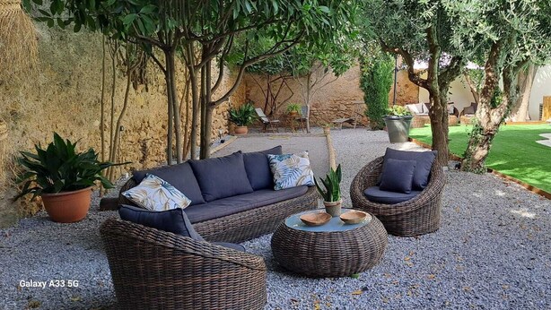 A cozy outdoor seating area with wicker furniture, a small table, and potted plants. - Le MAS CLEMENTINE (Puisserguier)