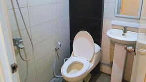 A small bathroom with a toilet, a sink, and a shower. - Hotel Karunia PKPRI (Purwodadi)