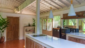 A kitchen with a white countertop, wooden cabinets, and a ceiling with exposed beams. - Peaceful Retreat with a Lush Garden & Open-Air Patio (Bantul)