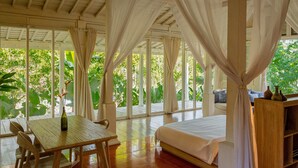 A bedroom with a bed, a wooden table, and a vase. - Peaceful Retreat with a Lush Garden & Open-Air Patio (Bantul)