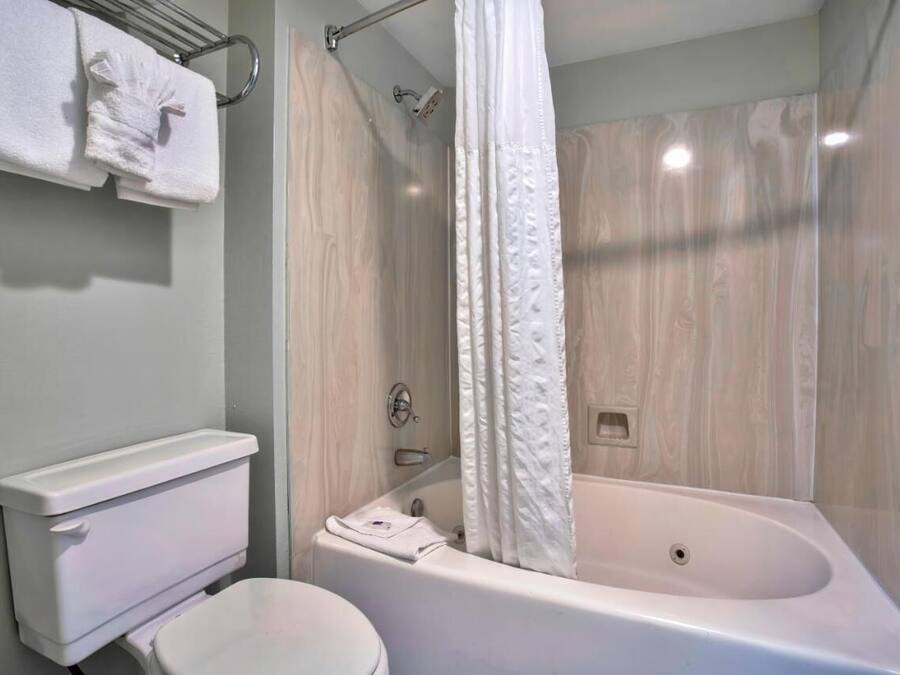 A bathroom with a bathtub, toilet, and towel rack.