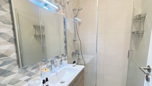Un baño moderno con cabina de ducha de vidrio, tocador con espejo y pared con diseño.