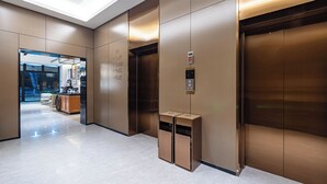 A modern elevator with a control panel and a trash bin. - HomeInn Plus Guozhan Liufang Subway Stn (Beijing)