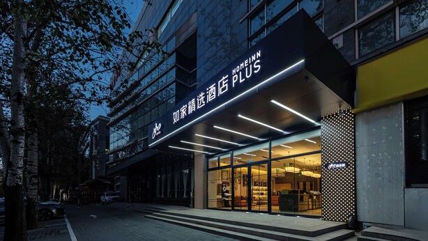 A modern hotel entrance with a glass facade and illuminated signage. - HomeInn Plus Guozhan Liufang Subway Stn (Beijing)