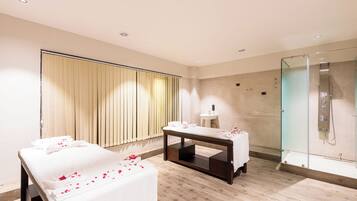 Relax in a serene space with a massage table, glass-enclosed shower, and large window.