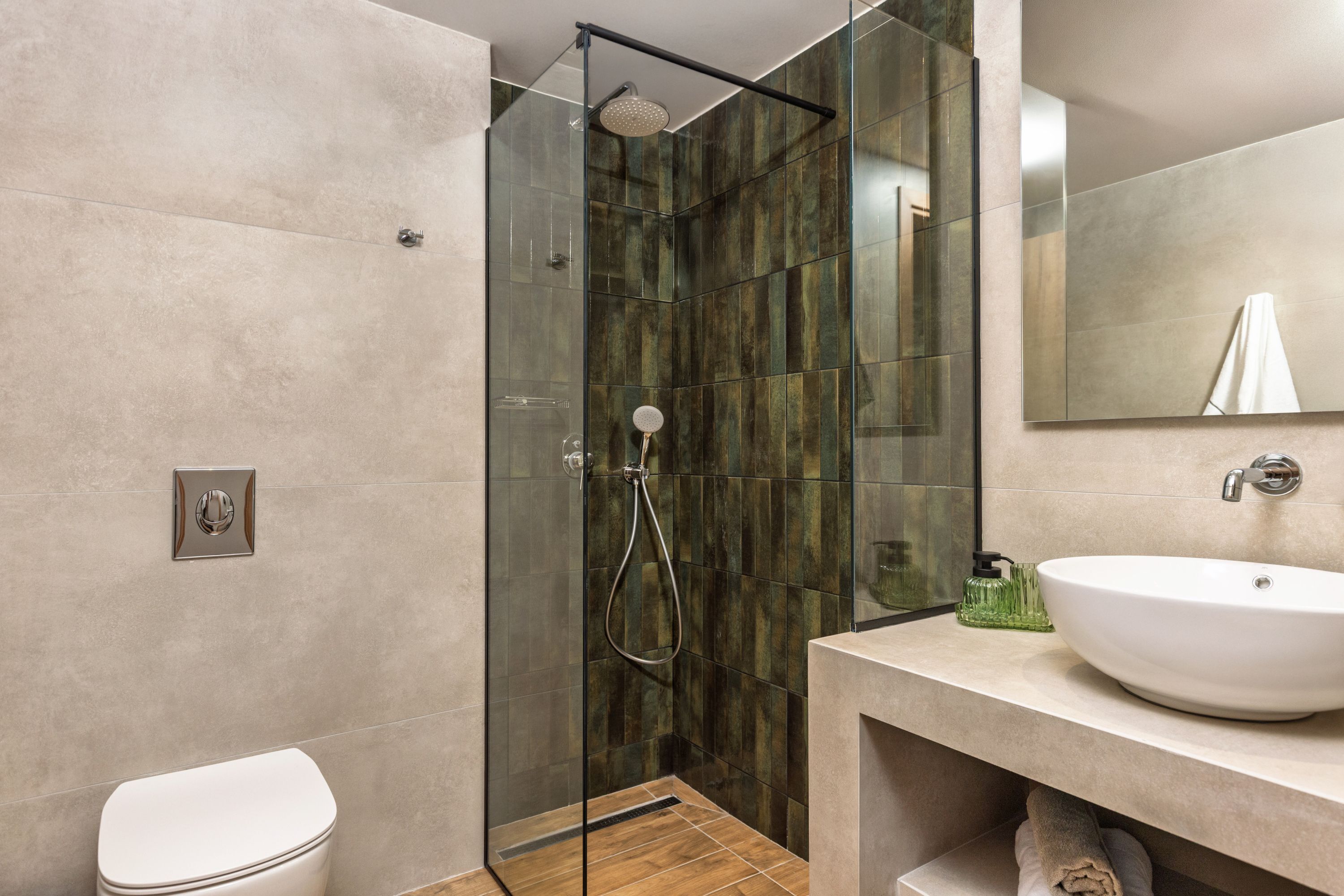 Un bagno moderno con doccia vetro, lavandino bianco e water.