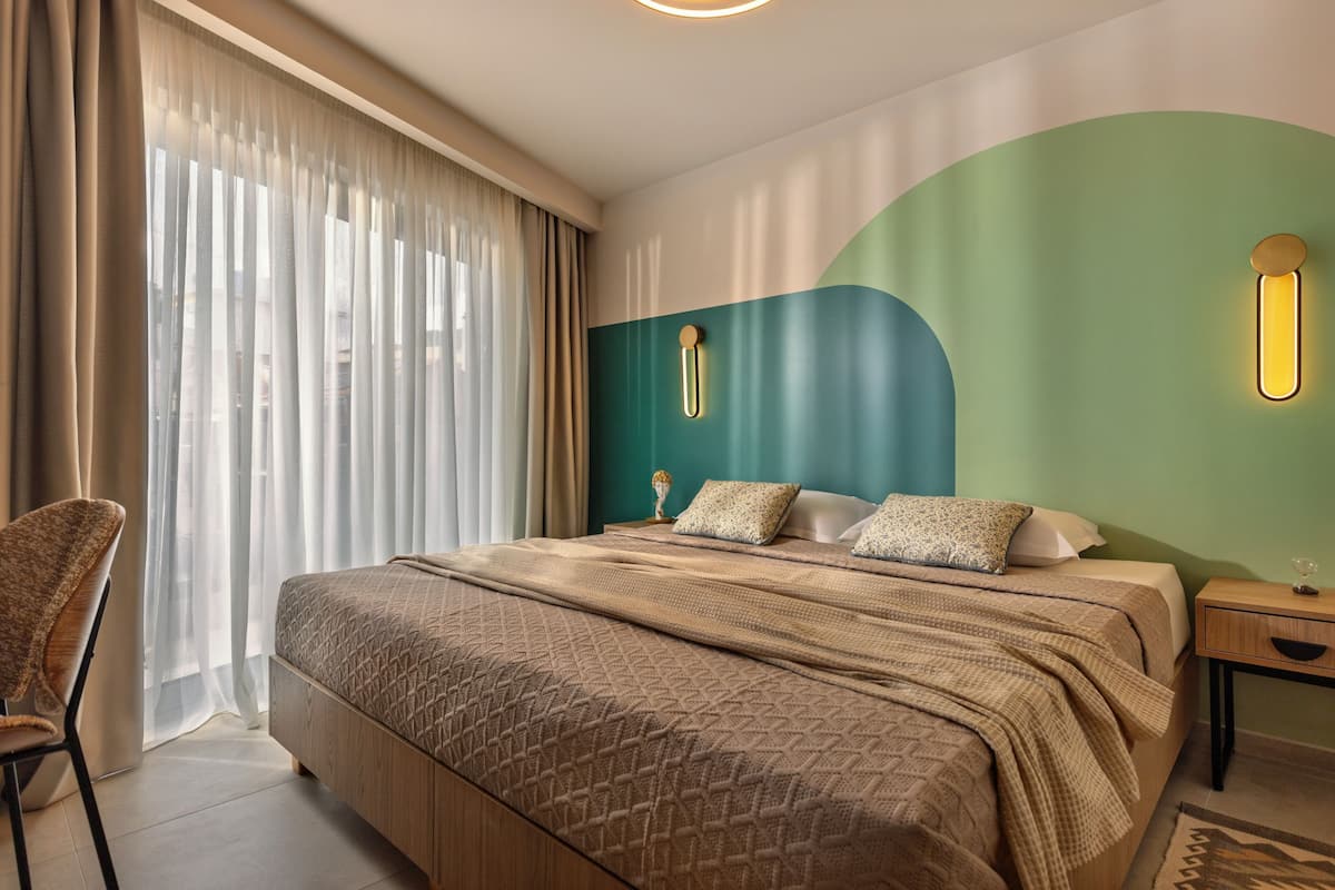 Une chambre d’hôtel comprenant un lit, une chaise, une table de chevet et un luminaire fixé au mur.