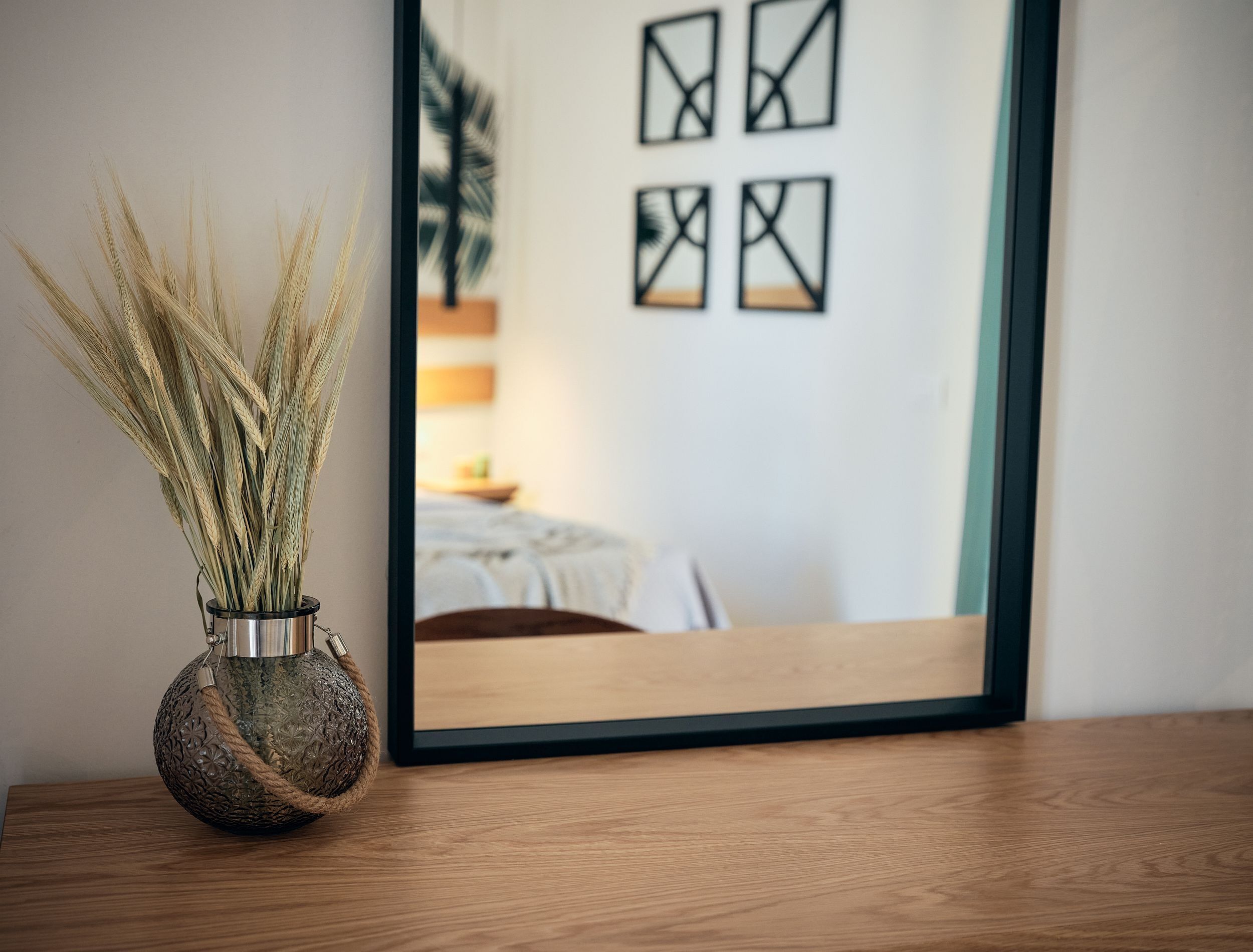 Une table en bois sur laquelle est posé un vase décoratif contenant des tiges de blé.