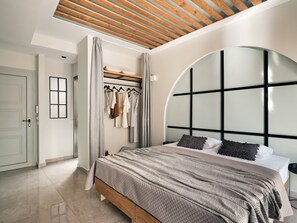 Un dormitorio con cama, armario, espejo y ventana con vistas al exterior.