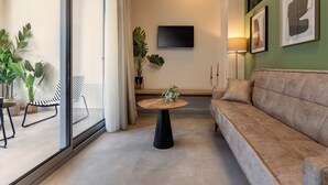 En moderne stue med sofa, rundt sofabord og et TV ophængt på væggen.