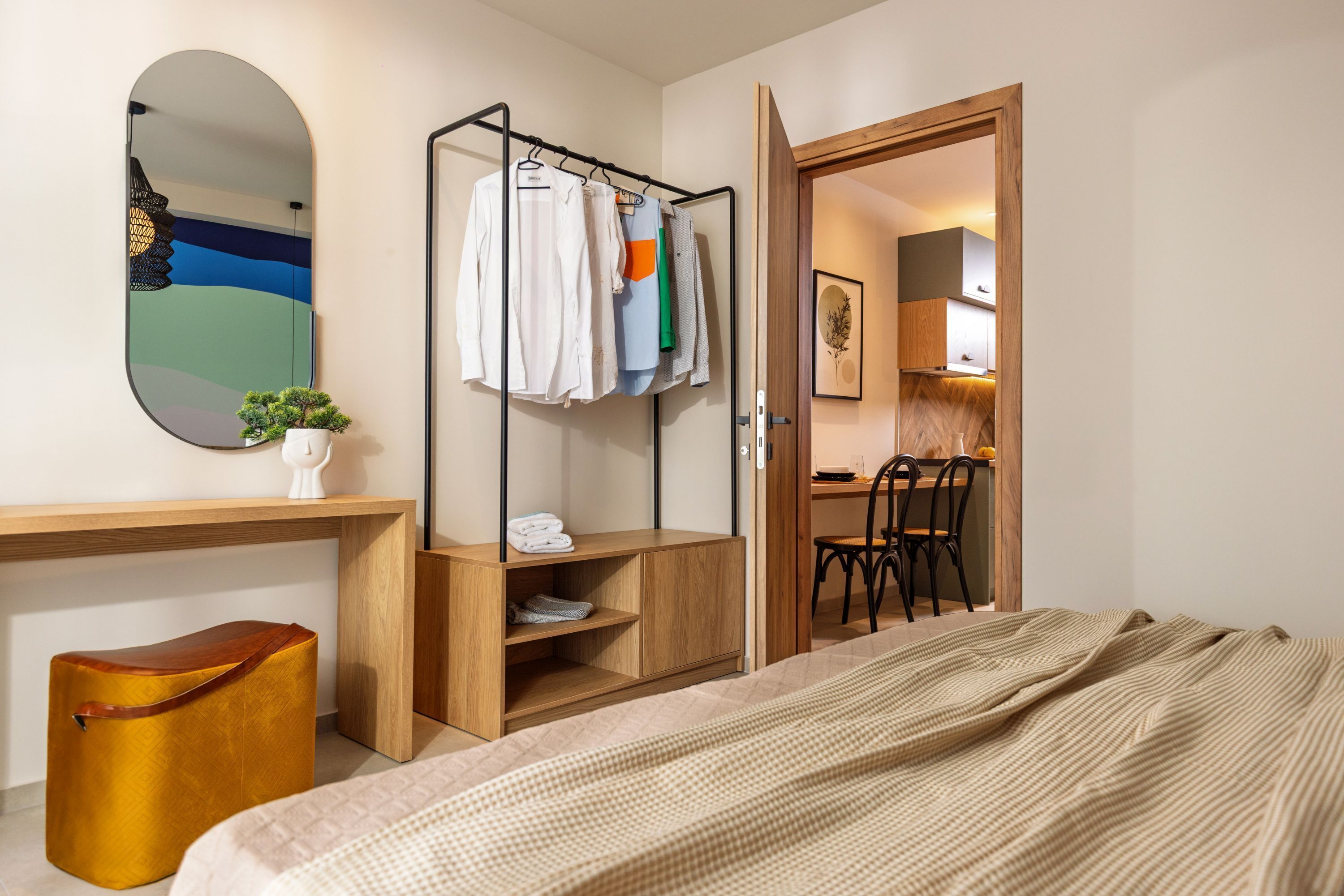 Ein Schlafzimmer mit einem Bett, einem hölzernen Schreibtisch, einem Spiegel und einem Kleiderständer.