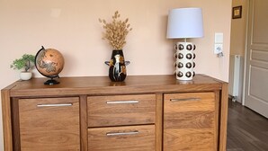A wooden cabinet with drawers and a globe on top, a vase with dried flowers, and a lamp on the right side.