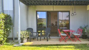 An outdoor patio with a table and chairs, a pergola, and potted plants.