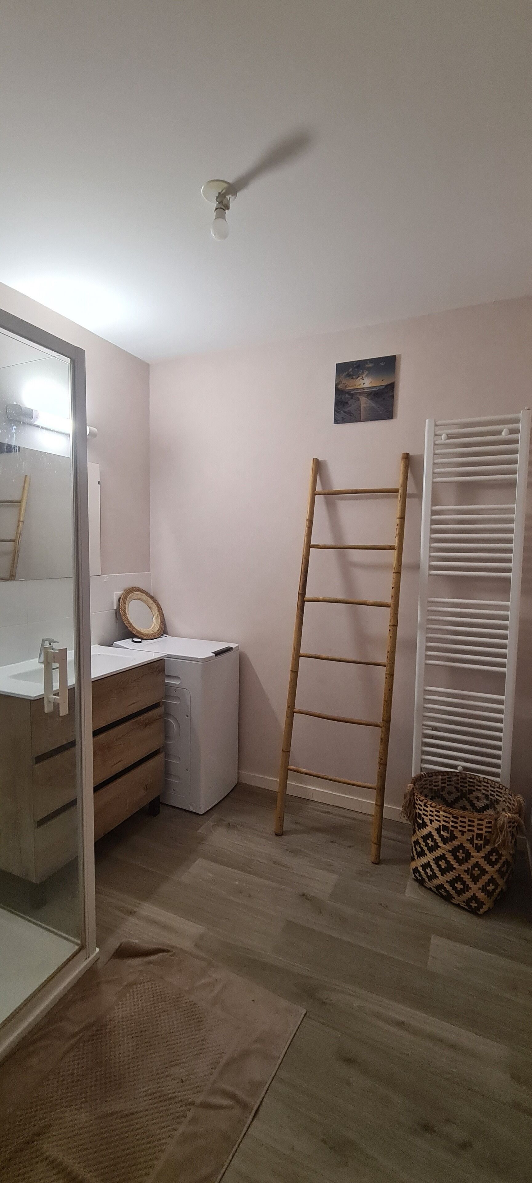 A bedroom with a wooden ladder, a white radiator, a small rug, and a bedside table with a mirror.