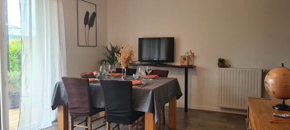 A dining area with a table set for four, a television on a stand, and a globe on a desk.