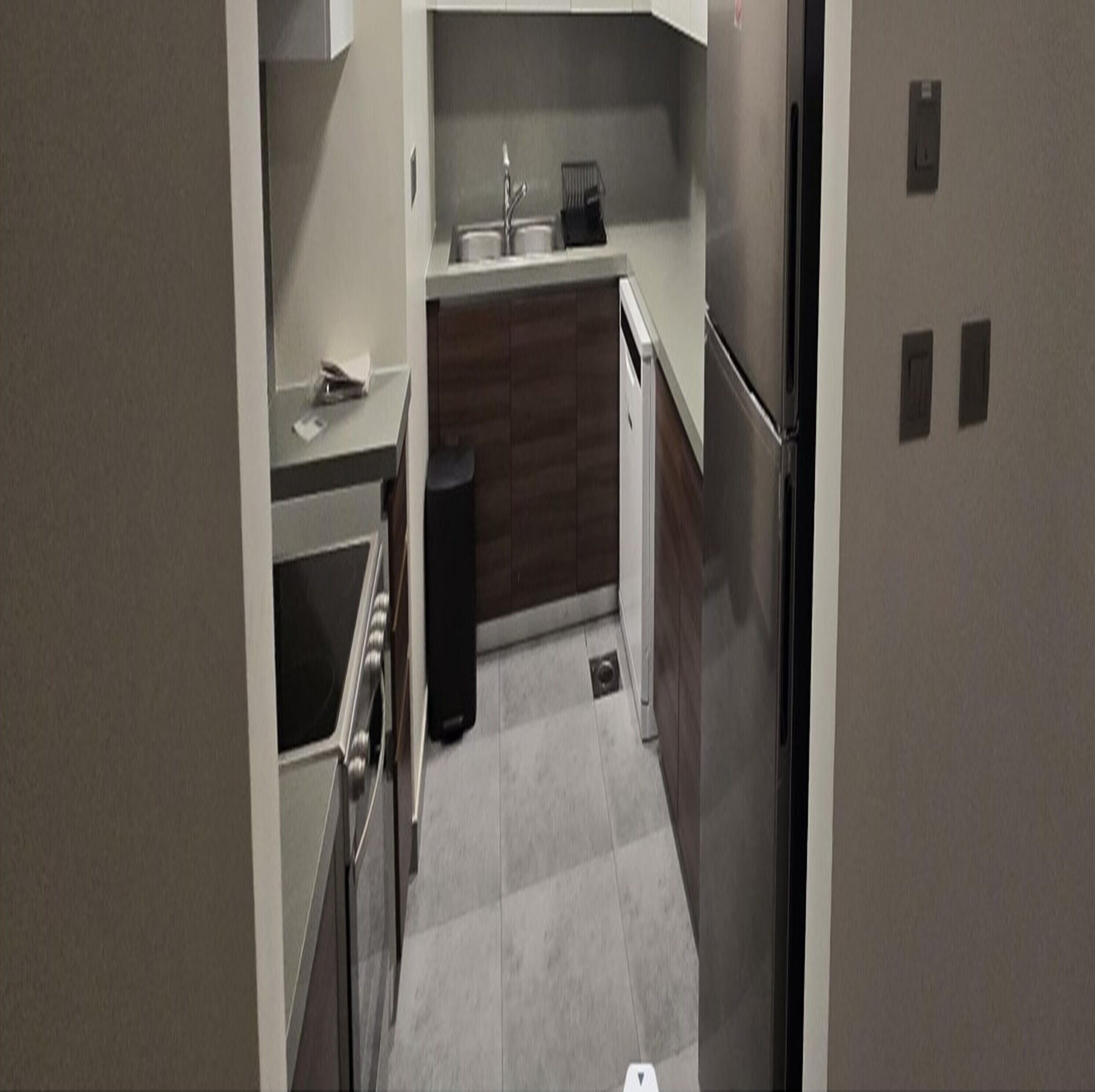 Una cocina compacta con lavamanos, estufa y refrigerador.